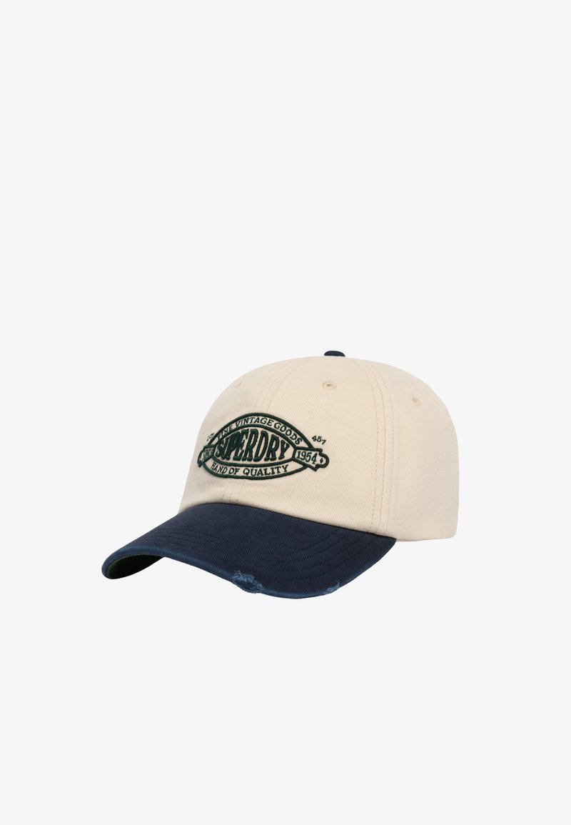 Beige og navy baseballkasket med broderet grønt logo med teksten "Superdry Fine Vintage Goods Hand of Quality 1954" på frontpanelet.