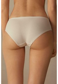 Slip hipster in cotone beige con una trama liscia, dotato di un elastico in vita a vita bassa e bordi inferiori senza cuciture per il massimo comfort.