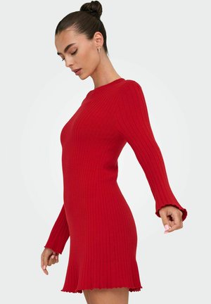 Rotes geripptes Strickkleid mit langen Glockenärmeln und gewelltem Saum, das eine figurschmeichelnde Silhouette und eine weiche Textur aufweist.