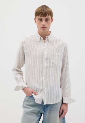 Camisa de boton medio clara con rayas, confeccionada en una tela suave, que presenta un bolsillo en el pecho y mangas largas con puños abotonados.