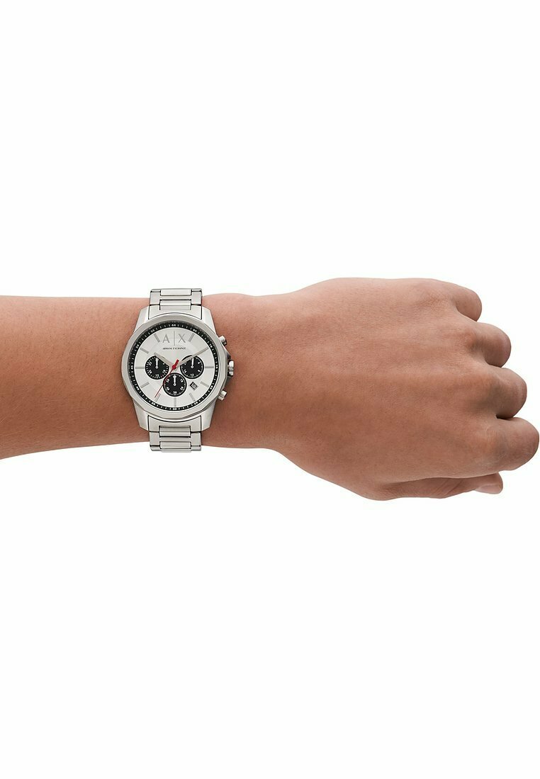 Zilveren roestvrijstalen horloge met een ronde witte wijzerplaat, zwarte subwijzerplaten, tachymeterschaal en schakelarmband zichtbaar op een pols.