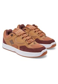 Bruna och vinröda sneakers med en blandning av läder och mocka, med nätinslag, runda snörningar och en vit mellansula. DC-logotyp synlig.