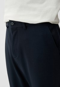 Navy broek met een op maat gemaakte ontwerp, vlakke voorkant en twee zijzakken met knoopsluiting, vervaardigd van een gladde stof.