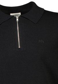 Polo shirt nera in maglia con zip frontale, collo piatto e logo ricamato discreto sul petto. Texture liscia e design aderente.