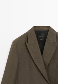 Veste de costume marron avec revers cranté et poche poitrine, étiquetée Massimo Dutti, présentée sur un fond blanc.