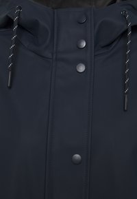 Navy-blauer wasserdichter Mantel mit hohem Kragen, Druckknöpfen und Kordelzug. Glatte, matte Oberfläche mit kontrastierenden schwarzen Akzenten.