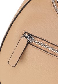 Beige Lederhandtasche-Ecke mit einem silbernen Reißverschluss und Zipp-Anhänger, mit einer strukturierten Oberfläche und dunkler kontrastierender Naht entlang der Kanten.