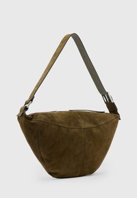 Borsa hobo in suede marrone con una forma curva, tracolla regolabile e dettagli in metallo argentato. Texture liscia senza motivi visibili.