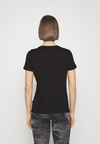 T-shirt nera in cotone con maniche corte, scollo rotondo e design aderente, abbinata a leggings grigi marmorizzati, vista da dietro.