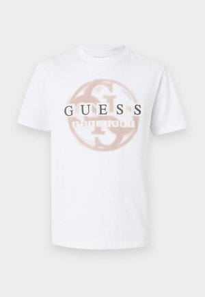 Hvit T-skjorte med korte ermer og beige sirkel-logo med teksten "GUESS EST. 1981" trykt over brystet.