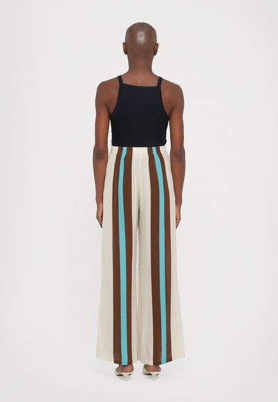 Top negru fără mâneci, asortat cu pantaloni largi crem, având dungi verticale maro și teal. Textură netedă, talie elastică pentru confort.