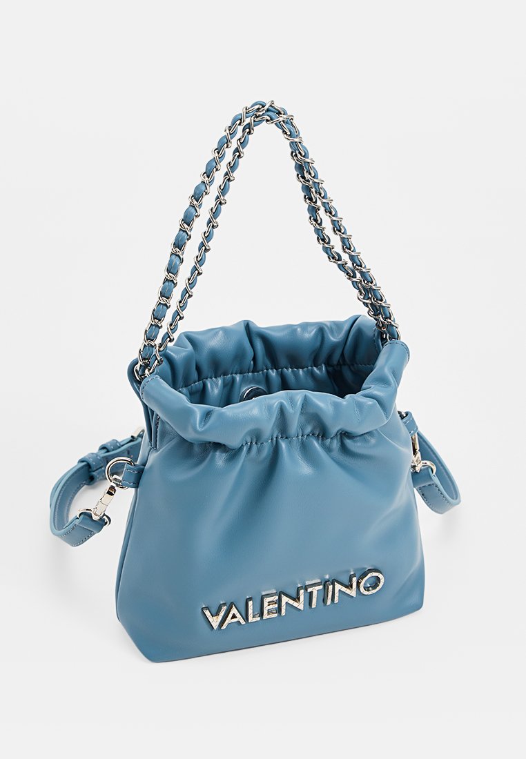 Sac en cuir souple bleu Valentino avec un haut froncé, des poignées en chaîne argentées et une bandoulière amovible sur fond blanc.