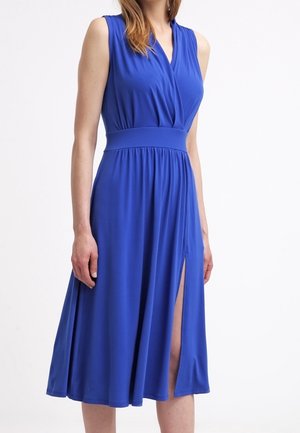 Vestito midi blu reale senza maniche con scollo a V, cintura aderente e spacco frontale indossato da una persona in piedi su sfondo bianco.