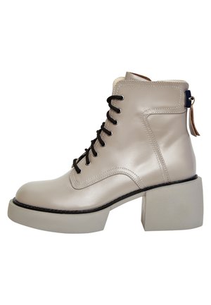 Bottine beige en cuir avec lacets noirs, talon bloc épais et languette à l’arrière, photographiée sur fond blanc.