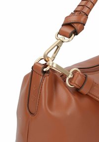 Bolso de mano de cuero color tan con un clip de metal dorado, correa trenzada y un sutil logo de la marca grabado en el lateral. Textura suave con una forma estructurada.