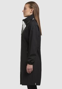 Giacca nera impermeabile con chiusura a zip, colletto alto, polsini elastici e cordino regolabile. Design semplice, elegante e funzionale.