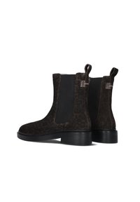 Pair of dark brown suede Chelsea boots with black elastic side panels and low stacked heels, shown from a rear angled view.