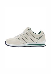 Scarpe sportive beige con tomaia in camoscio, dettagli verdi e tre strisce scure. Presentano una intersuola bianca e una suola in gomma per una buona aderenza.