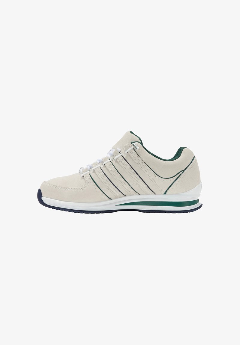 Scarpe sportive beige con tomaia in camoscio, dettagli verdi e tre strisce scure. Presentano una intersuola bianca e una suola in gomma per una buona aderenza.