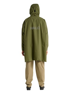 Person trägt eine olivgrüne Kapuzenregenjacke mit dem Schriftzug „HALO“ auf dem Rücken, beigen Hosen und schwarzen Schuhen und steht mit dem Rücken zur Kamera.