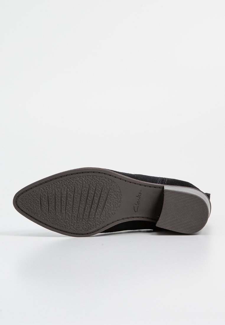 Czarne zamszowe buty z okrągłym noskiem i skromnym obcasem. Teksturowana gumowa podeszwa z rowkami dla lepszej przyczepności. Wytłoczone logo marki "Clarks".
