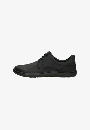 Chaussures noires à lacets en matériau synthétique, avec une texture lisse, un bout rond et une semelle en caoutchouc flexible, avec un minimum de détails.