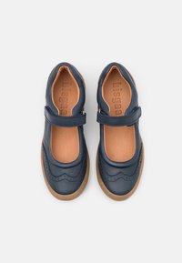 Granatowe skórzane buty typu Mary Jane z falbaniastym wzorem i beżową wkładką. Posiadają pasek oraz gumową podeszwę dla lepszej przyczepności i komfortu.