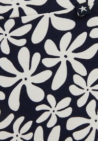 Sötétkék szövet, nagyméretű, fehér virágokkal és fekete középpontokkal díszítve. Simább tapintású, puha, rugalmas anyag.