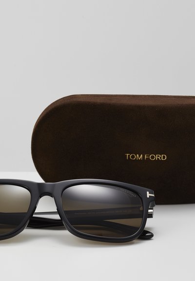 Black plastic sunglasses with gradient lenses, silver accents, and T logo. Includes a brown suede hard case with "TOM FORD" embossed in gold.