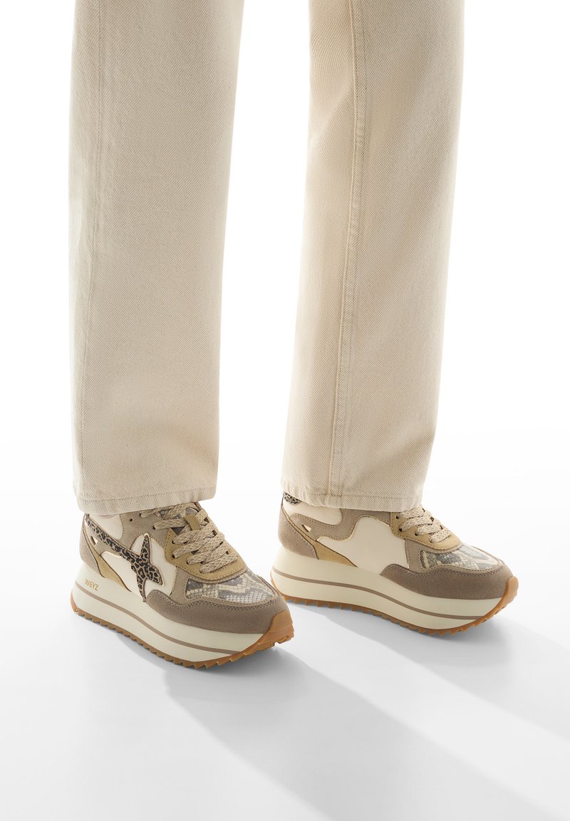 Sneaker platform beige con stampa effetto serpente texturizzata, dettagli in crema liscia e chiusura stringata tonale. Indossate con pantaloni chiari e morbidi.