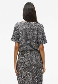 Czarna sukienka z cekinami w odcieniu ciemnoszarym, z krótkimi rękawami, luźnym krojem i okrągłym dekoltem, charakteryzująca się fakturową powierzchnią i błyszczącymi akcentami na całej długości.
