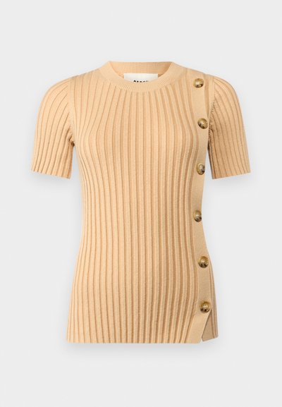 Kortermet ribbestrikket topp i lys beige, med knappdetaljer på siden og en tettsittende silhuett for et strukturert utseende.