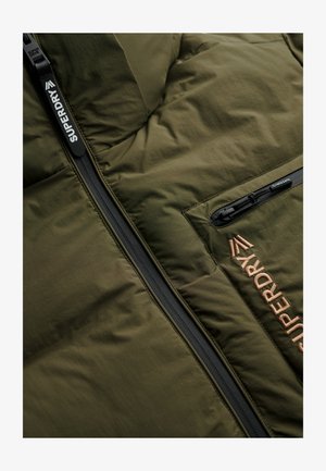 Gewatteerd jack in olijfgroen, met gewatteerde textuur, ritssluiting aan de voorkant met branding en een contrasterende zwarte ritssluitingzak.