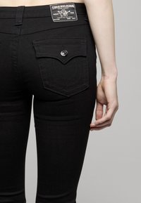 Zwarte denim skinny jeans met een kenmerkend stikselpatroon op de zakken en een merklabel op de tailleband. Voorzakken zijn niet zichtbaar.