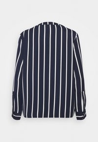 Námořnická košile s vertikálními bílými pruhy, dlouhými rukávy, kulatým výstřihem a ohrnovacími manžetami na rukávech, vyrobená z lehkého materiálu.