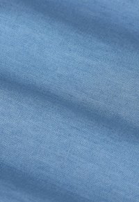 Tissu bleu clair avec une texture lisse, présentant un motif de tissage fin. La surface semble uniforme sans motifs ou accents visibles.