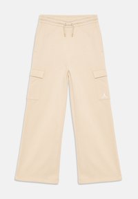 Beige wide-leg cargo pants with elastic waistband, drawstring, side flap pockets, and small white Jumpman logo on right pocket.