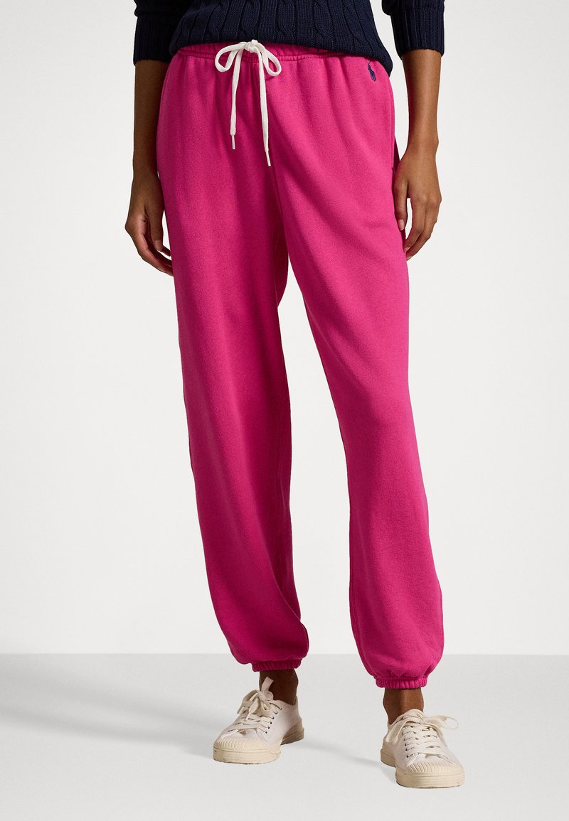 Rosa bomullssweatpants med elastiska mudd och justerbar dragsko i midjan, kombinerat med beige snörskor.