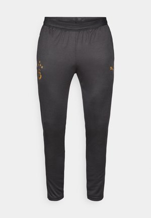 Pantalones deportivos negros con tela texturizada, con un logo y emblema dorados cerca de la cintura, cintura elástica y diseño de pierna cónica.