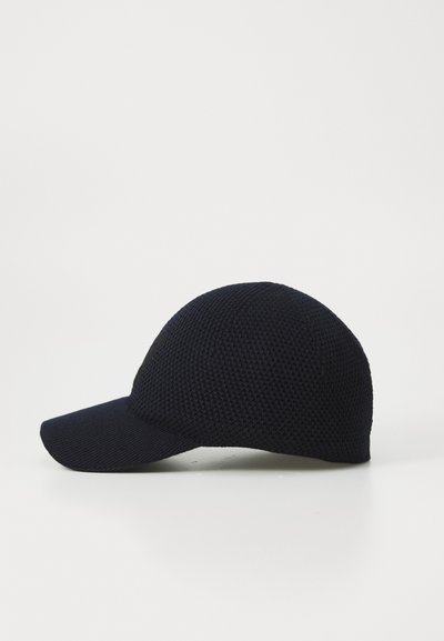 Mørk marineblå teksturert strikket baseballcap med buet skjerm, vist fra siden på hvit bakgrunn.