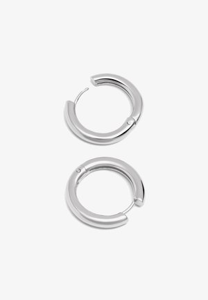 Srebrne kolczyki w kształcie obręczy o gładkim, zaokrąglonym designie. Kolczyki posiadają bezpieczne zapięcie oraz polerowane wykończenie, które podkreśla ich refleksyjną jakość.