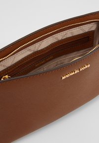 Pochette con zip in pelle sintetica marrone, dotata di hardware dorato e numerosi scomparti interni. Foderata con un tessuto beige.