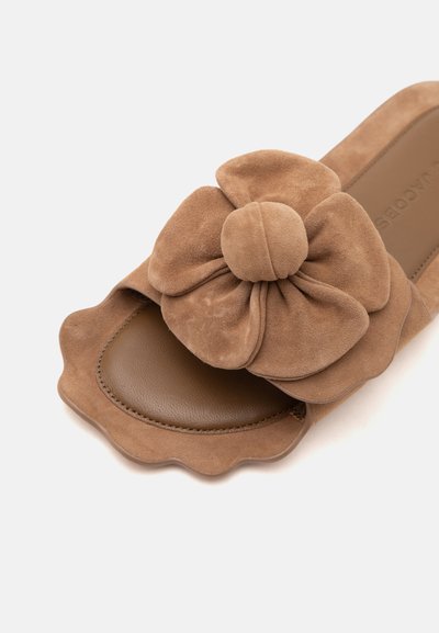 Sandale mule en daim marron avec bords festonnés et grande décoration fleur en tissu sur la bride au-dessus d'une semelle en cuir.