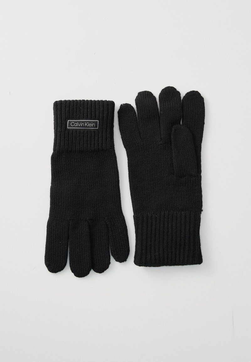 Sorte strikkede hansker med ribbestrikkede mansjetter, et merke med "Calvin Klein", og en standard fem-finger design. Stoffs tekstur virker myk.