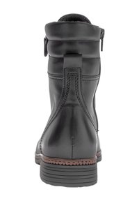 Bota negra de cuero hasta el tobillo con cuello acolchado, cremallera lateral, costuras detalladas, ribete marrón sobre la suela negra estriada, vista desde atrás.