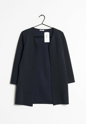 Mörk marinblå kofta med öppen frontdesign, trekvartsärmar, texturerad tyg och en hängande etikett. Slät innerfoder.