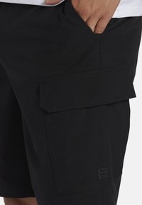Sorte cargo shorts lavet af letvægtsmateriale. Har en sidelomme med klap, synliggjorte detaljer og et lille logo-mærke i kanten.