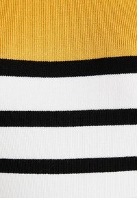 Tissu tricoté présentant des rayures horizontales jaune, noir et blanc. La texture est côtelée, avec des largeurs variées de rayures.