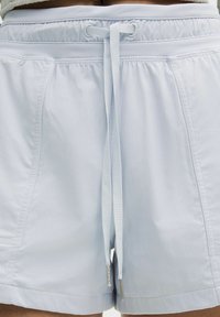 Pantalones cortos azul claro con un acabado texturizado, cinturilla elástica y un cordón con puntas metálicas. Cuenta con bolsillos laterales y un corte relajado.