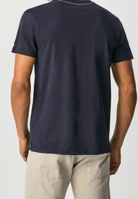 Marineblaue Baumwoll-T-Shirt mit kurzen Ärmeln, Rundhalsausschnitt und kontrastierendem weißen Stich entlang des Ausschnitts. Lässige Passform, schlichte Rückseite.